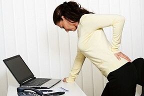 uma mulher tem dores nas costas na região lombar